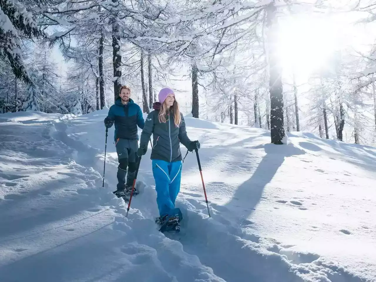Mann und Frau wandern mit Schneeschuhen im Wald